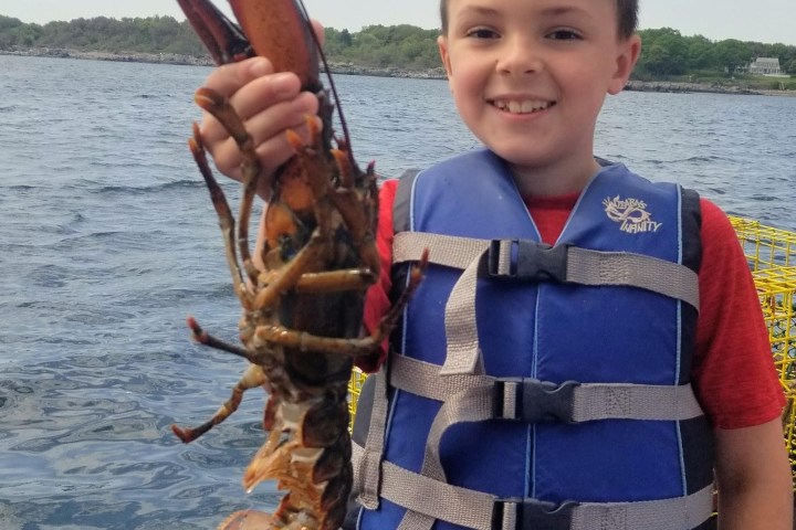 a little boy standing next to a body of water