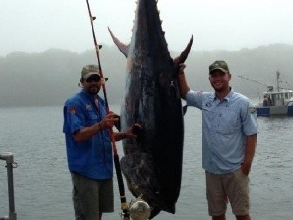 a man holding a fish on a boat in a body of water