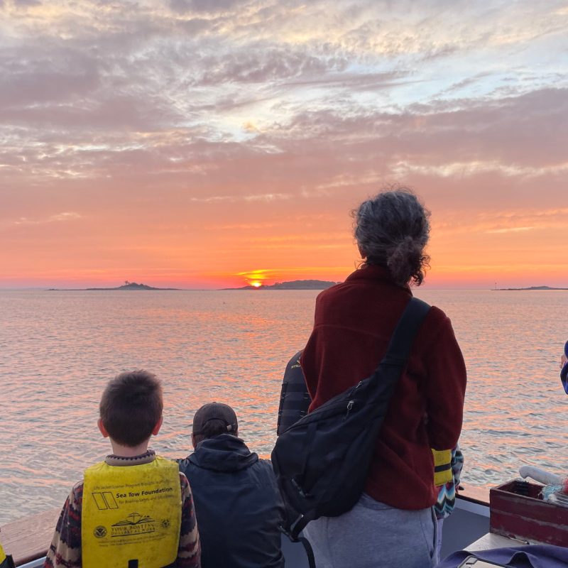 a group of people standing next to a young boy flying a kite