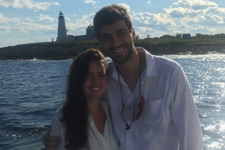 a man and a woman standing in front of a body of water